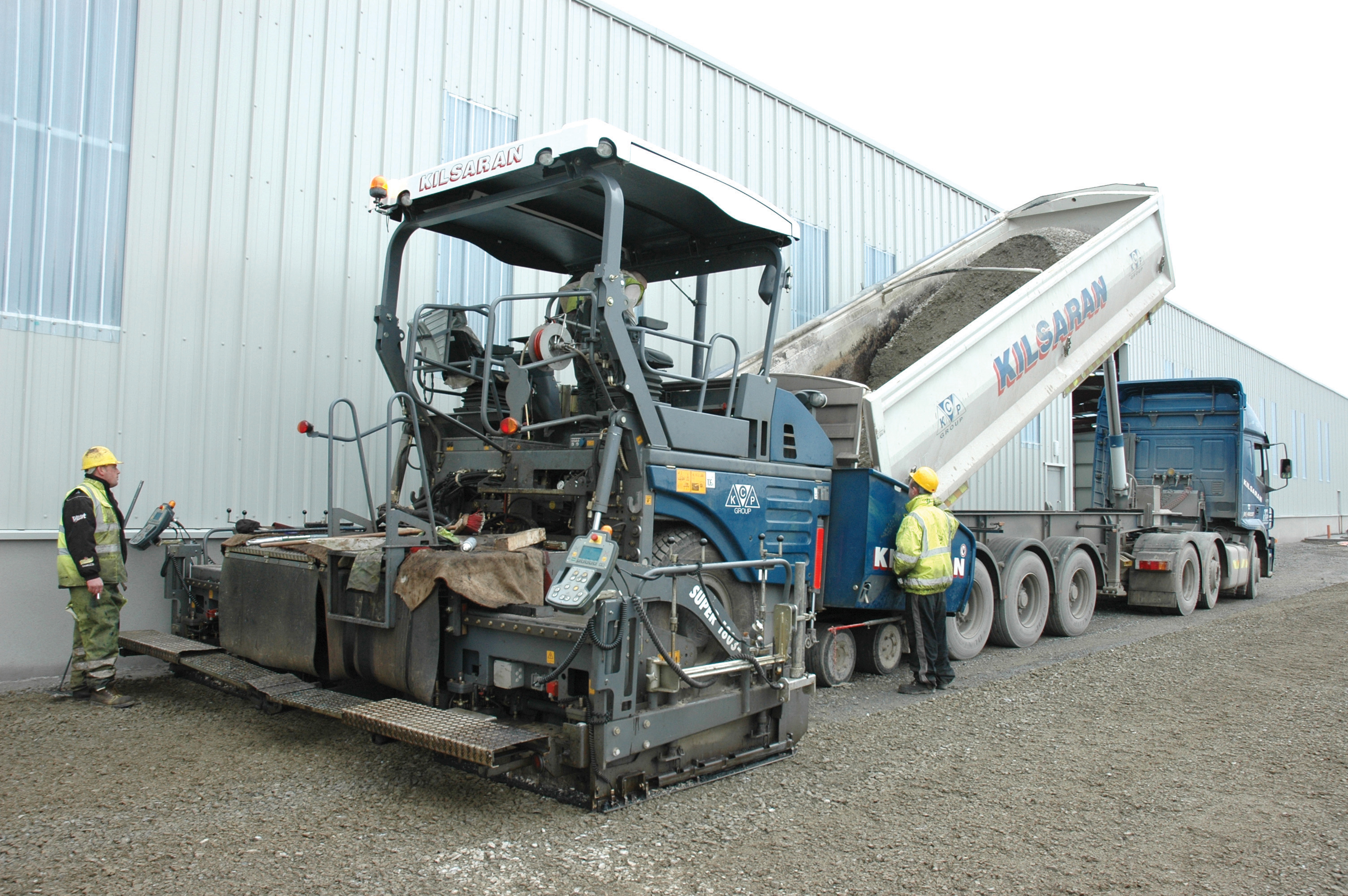 Dump truck emptying concrete into a Vogele paver 