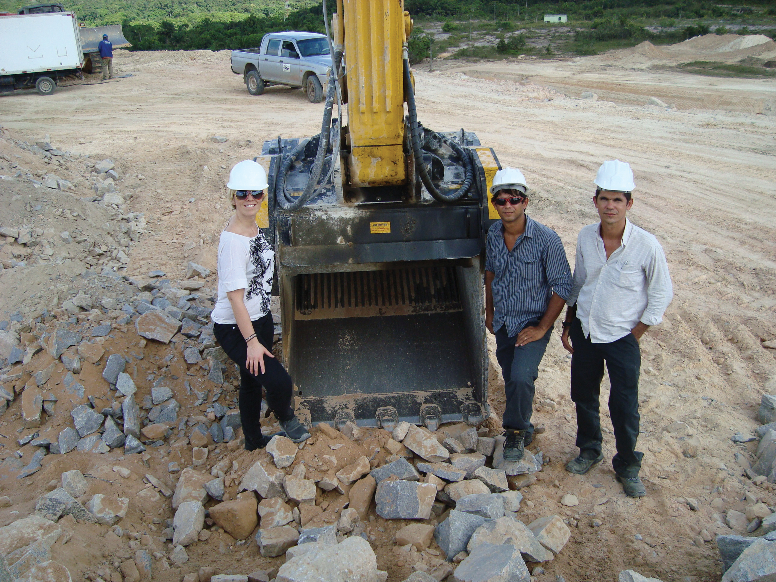 3 people standing next to MB crusher bucket