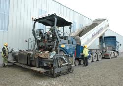 Dump truck emptying concrete into a Vogele paver 