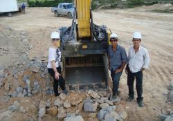 3 people standing next to MB crusher bucket