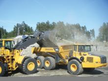 Excavator  unloading onto Volvo dump truck 