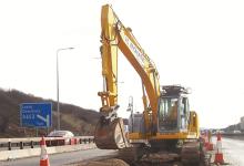 A New Holland E235B reduced tailswing tracked excavator at work on the motorway 