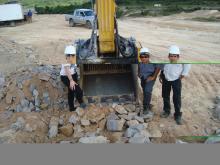 3 people standing next to MB crusher bucket